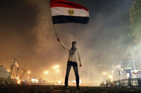 An Egyptian protester waves his national flag as he is surrounded by tear gas fired by riot police in Cairos Tahrir square on January 25, 2013. Protesters stormed a regional government headquarters and clashed with police as mass rallies shook Egypt on the second anniversary of a revolt that ousted Hosni Mubarak and brought Islamists to power.    TOPSHOTS/AFP PHOTO/MAHMOUD KHALED